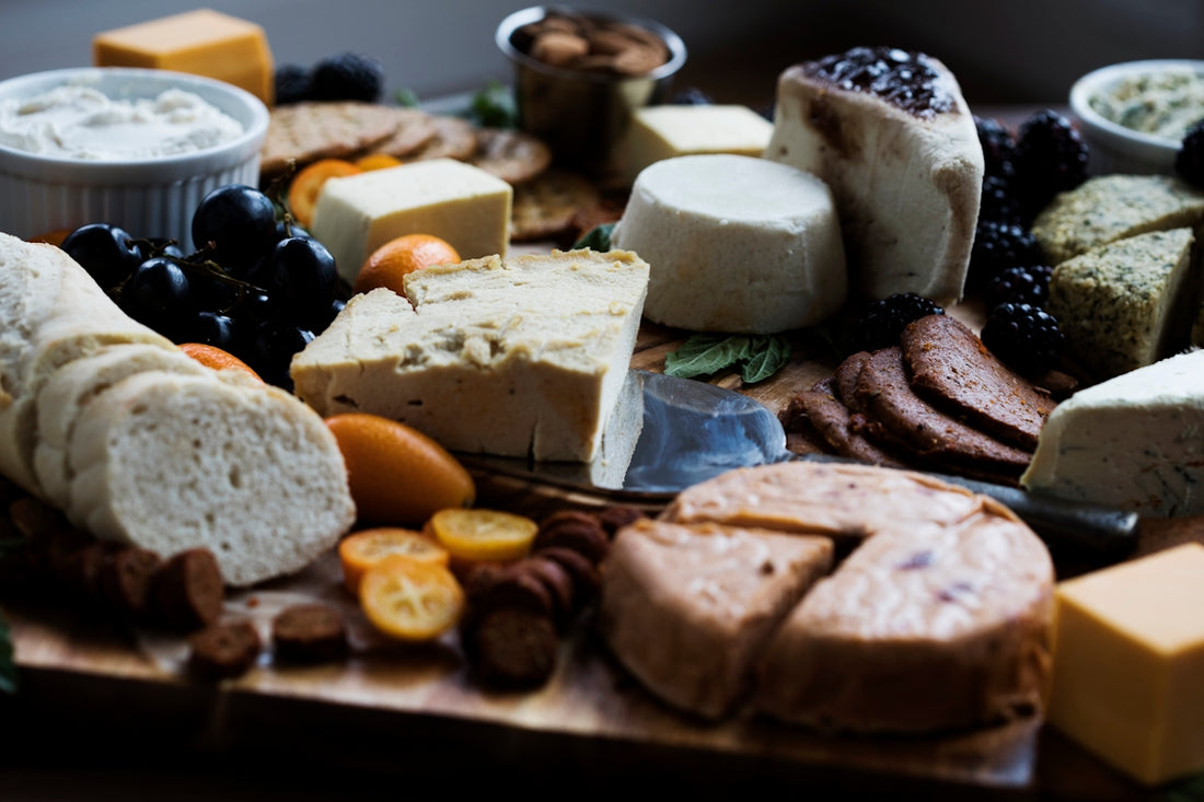 a wooden cutting board topped with lots of different types of cheese
