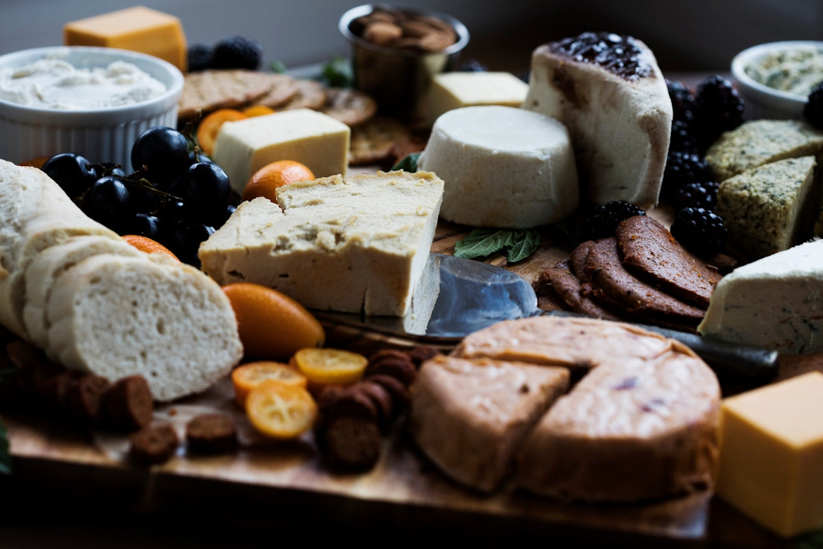 a wooden cutting board topped with lots of different types of cheese