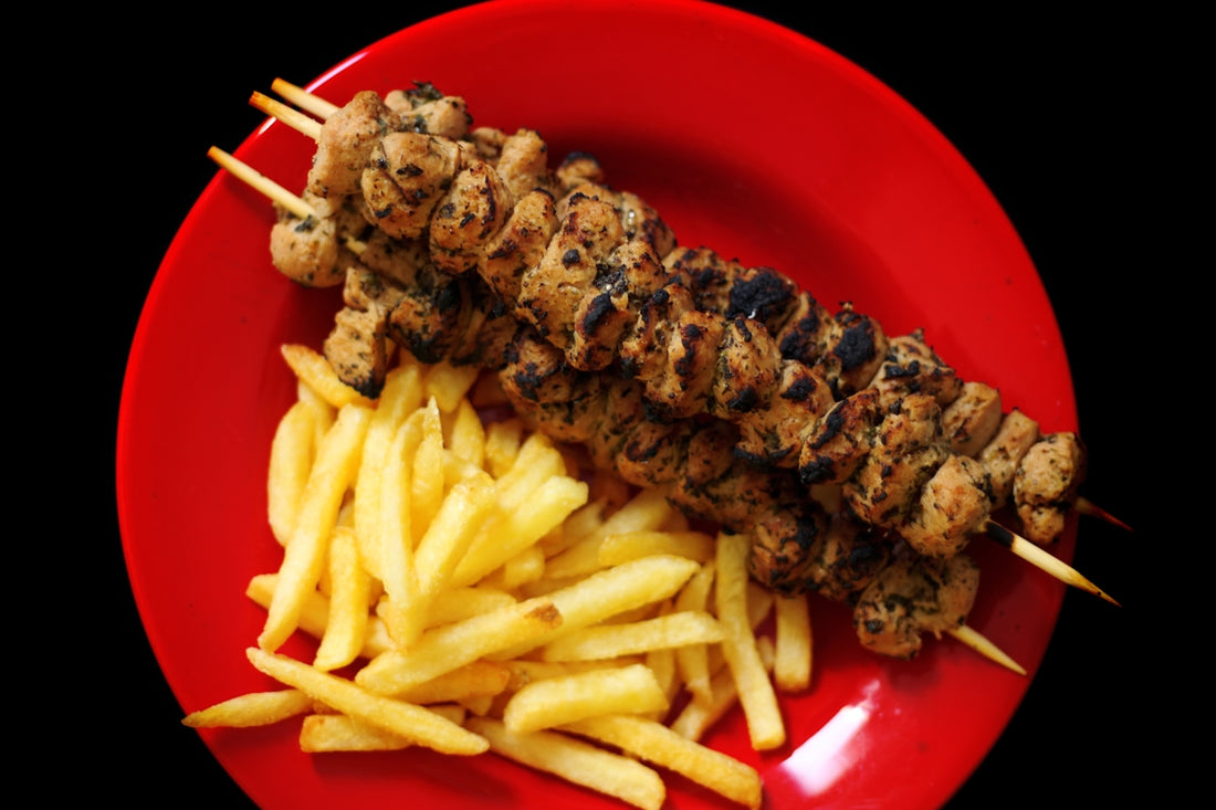 A red plate topped with french fries and skewered meat